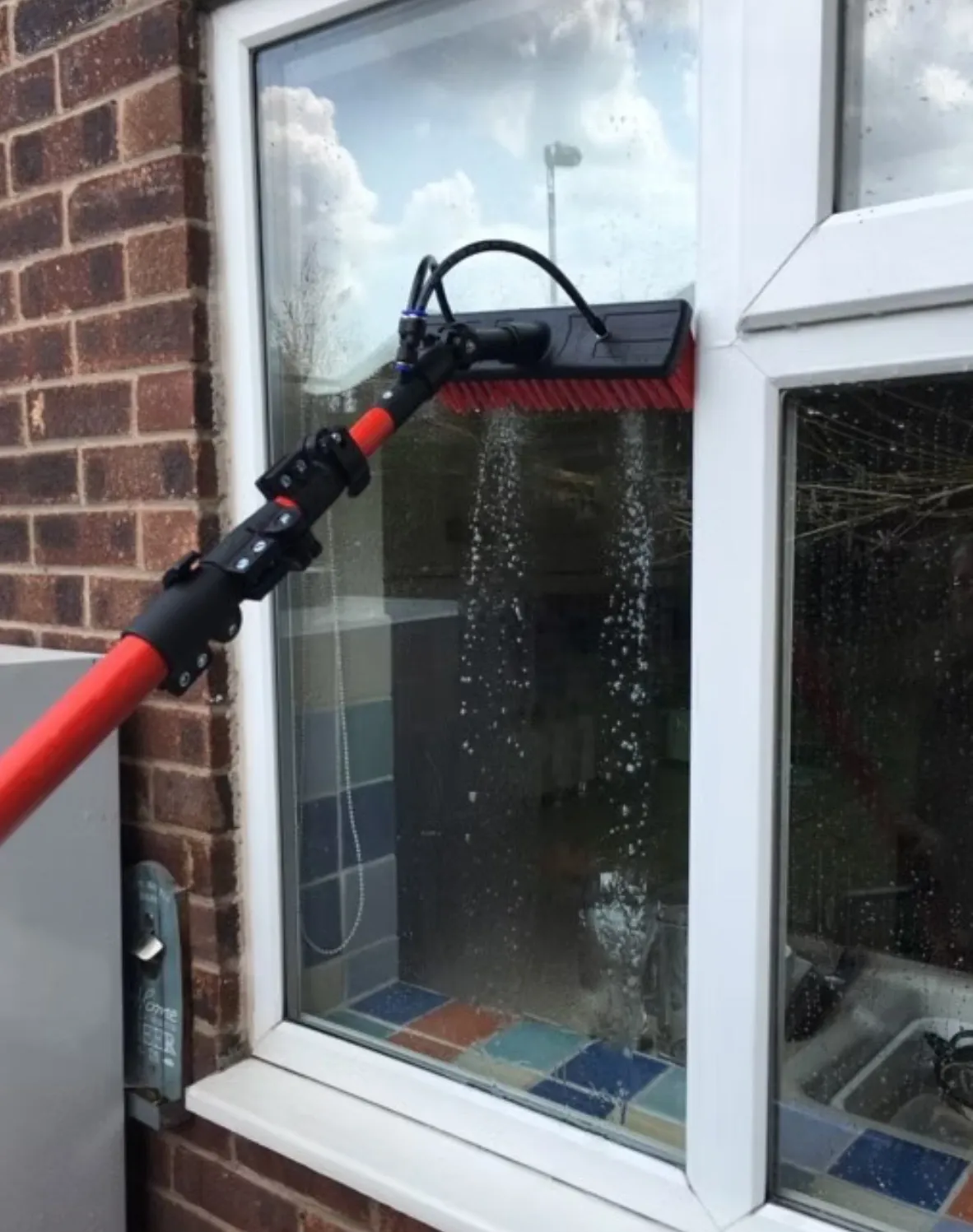 Water-fed pole cleaning a UPVC window in London